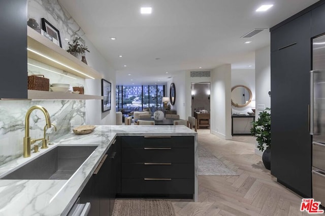 kitchen with light stone counters, sink, tasteful backsplash, and light parquet flooring