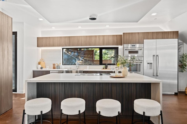 kitchen featuring stainless steel appliances, dark hardwood / wood-style floors, a kitchen breakfast bar, and a kitchen island