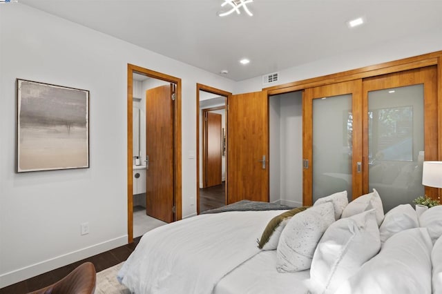 bedroom with dark wood-type flooring, connected bathroom, and a closet