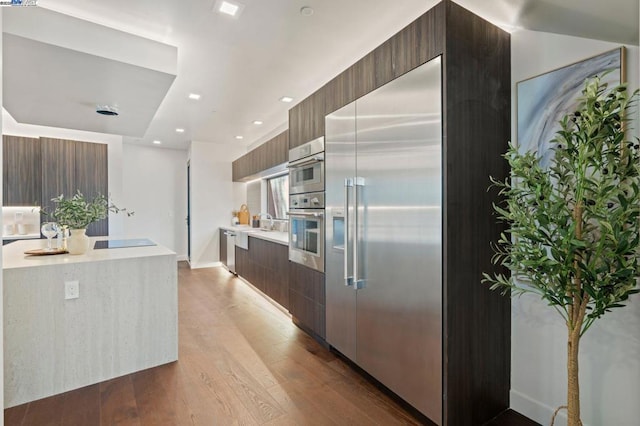 kitchen with stainless steel built in fridge, sink, and light hardwood / wood-style floors