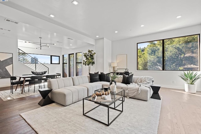 living room featuring a notable chandelier, wood-type flooring, and plenty of natural light