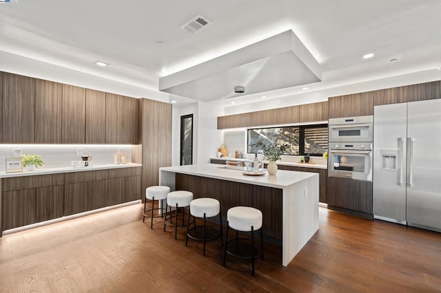 kitchen featuring dark hardwood / wood-style floors, a kitchen island, a breakfast bar, and appliances with stainless steel finishes