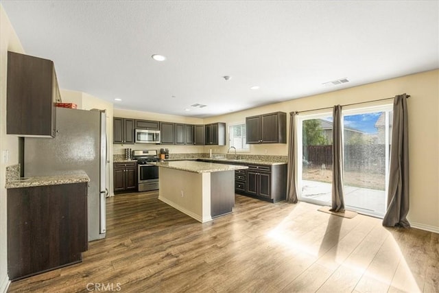 kitchen featuring visible vents, dark wood-type flooring, a sink, a kitchen island, and stainless steel appliances