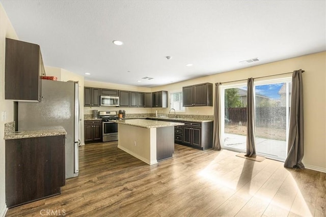 26605 Rose Bud Ln, Moreno Valley, CA 92555 - kitchen with appliances with stainless steel finishes, a kitchen island, dark wood-type flooring, dark brown cabinets, and recessed lighting