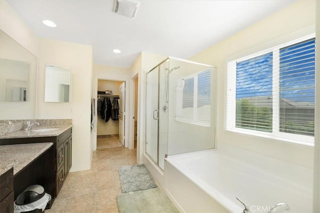 full bathroom with a bath, a stall shower, vanity, and a walk in closet