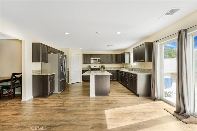 kitchen with visible vents, a kitchen island, light wood-style flooring, appliances with stainless steel finishes, and a sink