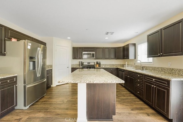 kitchen featuring visible vents, dark wood finished floors, a sink, stainless steel appliances, and a center island