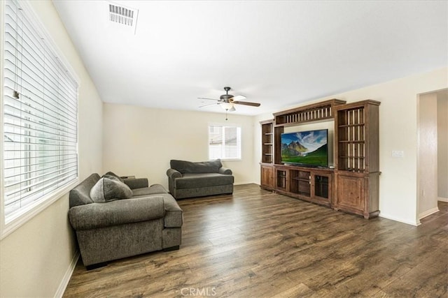 living area featuring visible vents, baseboards, wood finished floors, and a ceiling fan