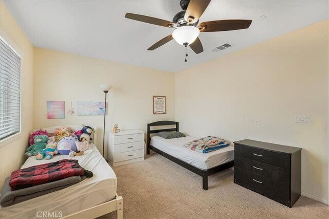 bedroom with ceiling fan, visible vents, and light carpet