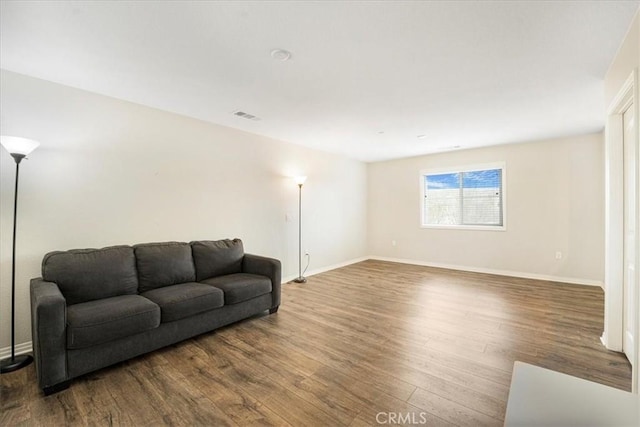 living area with visible vents, baseboards, and wood finished floors