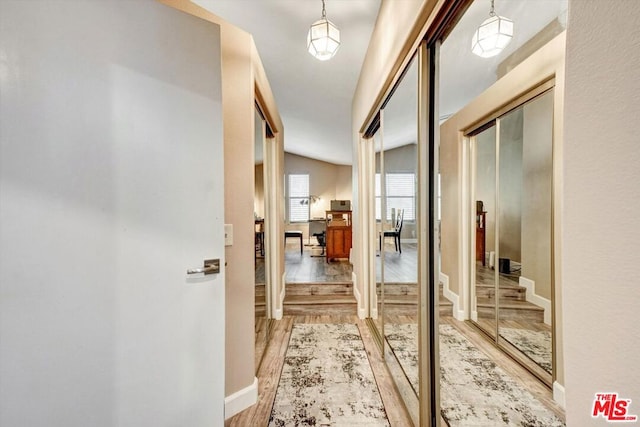 hallway featuring vaulted ceiling and light hardwood / wood-style flooring