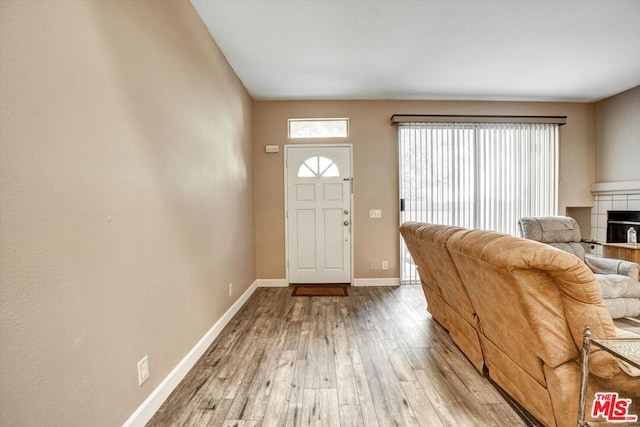 entryway with wood-type flooring and a tiled fireplace