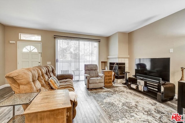 living room with a tile fireplace and light wood-type flooring