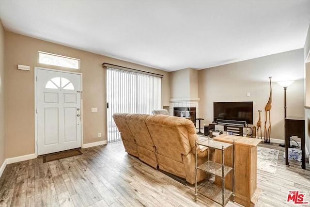 living room with a tile fireplace and light wood-type flooring