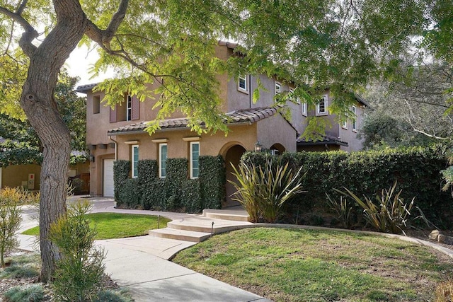 mediterranean / spanish-style house featuring a garage and a front lawn