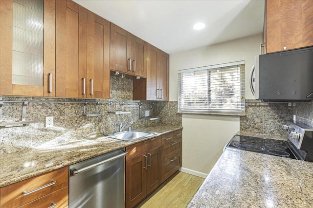 kitchen featuring sink, decorative backsplash, stainless steel appliances, light stone countertops, and light hardwood / wood-style flooring