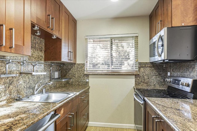 kitchen featuring appliances with stainless steel finishes, stone countertops, sink, and light wood-type flooring