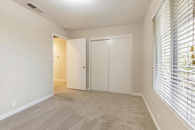 unfurnished bedroom featuring light carpet and a closet