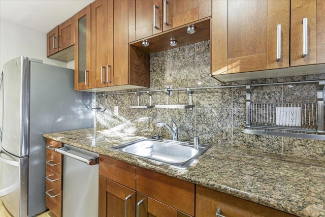 kitchen featuring tasteful backsplash, appliances with stainless steel finishes, sink, and stone counters