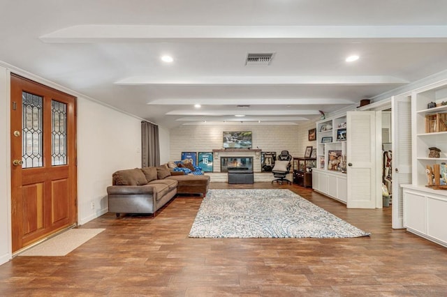 living room featuring beamed ceiling, brick wall, and light hardwood / wood-style floors