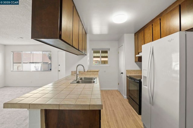 kitchen with tile countertops, black electric range oven, sink, and white fridge with ice dispenser