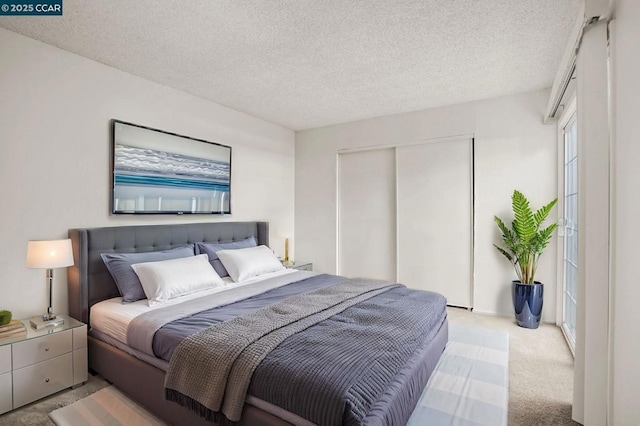 bedroom with light colored carpet, a closet, and a textured ceiling