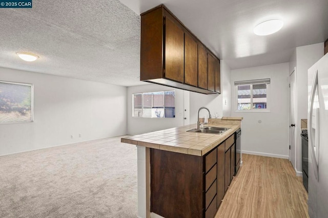 kitchen featuring plenty of natural light, tile countertops, sink, and dark brown cabinets