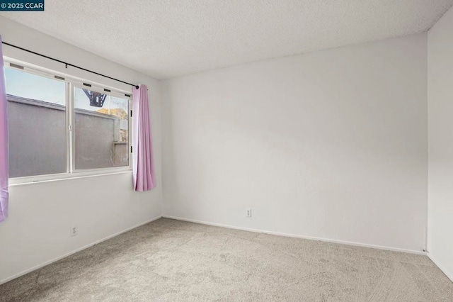 empty room with light carpet and a textured ceiling