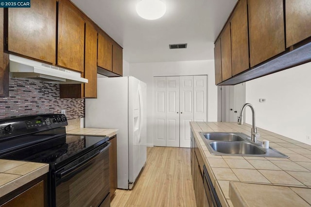 kitchen featuring black / electric stove, tile countertops, tasteful backsplash, sink, and light hardwood / wood-style flooring