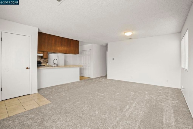 unfurnished living room with light carpet and a textured ceiling