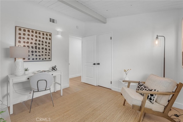 living area with beamed ceiling and light hardwood / wood-style floors