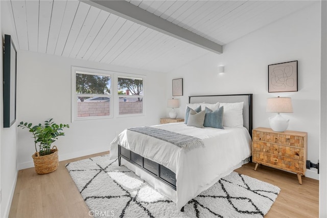 bedroom with vaulted ceiling with beams and light wood-type flooring