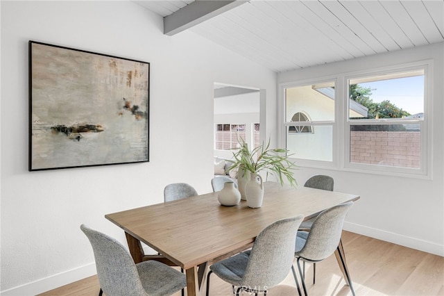 dining room featuring vaulted ceiling with beams and light hardwood / wood-style floors