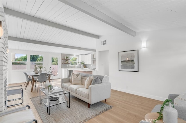 living room featuring vaulted ceiling with beams and light hardwood / wood-style flooring