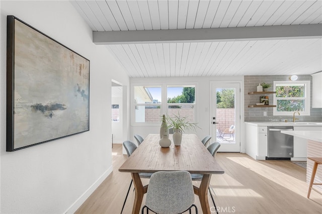 dining space with beamed ceiling, sink, and light wood-type flooring