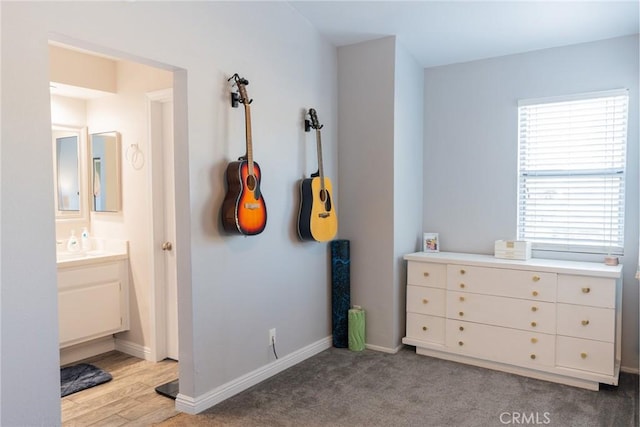 bedroom with connected bathroom, light carpet, and multiple windows