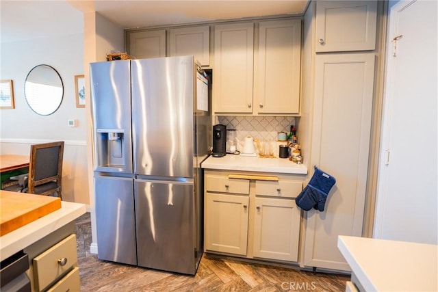 kitchen with stainless steel refrigerator with ice dispenser, gray cabinets, and backsplash