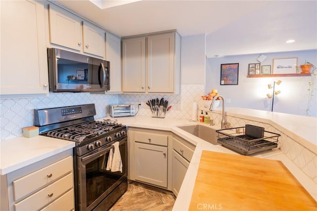 kitchen featuring stainless steel appliances, gray cabinets, sink, and decorative backsplash