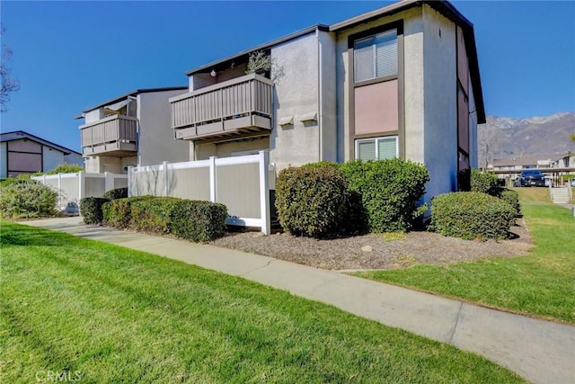 view of home's exterior with a balcony and a yard