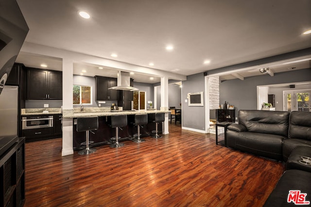 living room with sink, beam ceiling, and dark wood-type flooring