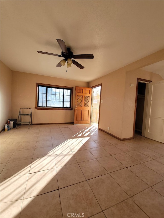 tiled empty room featuring ceiling fan