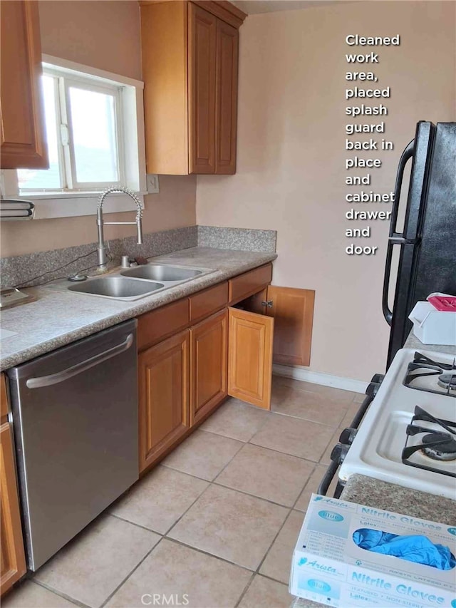 kitchen featuring black refrigerator, sink, light tile patterned floors, and stainless steel dishwasher