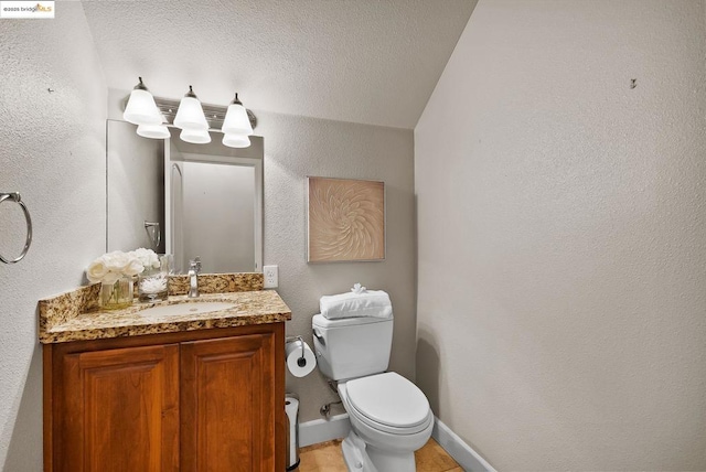 bathroom with vanity, toilet, and a textured ceiling