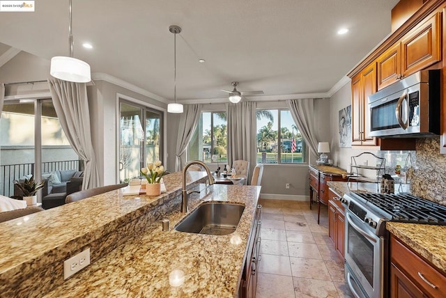 kitchen featuring hanging light fixtures, light stone countertops, appliances with stainless steel finishes, and sink