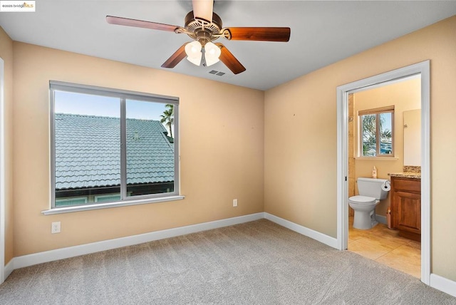 unfurnished bedroom with ceiling fan, light carpet, and ensuite bath