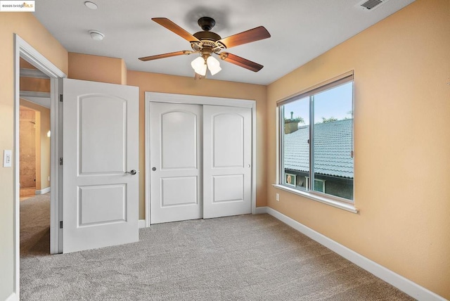 unfurnished bedroom with light carpet, a closet, and ceiling fan