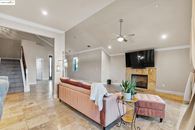 living room featuring a tiled fireplace, ornamental molding, lofted ceiling, and ceiling fan