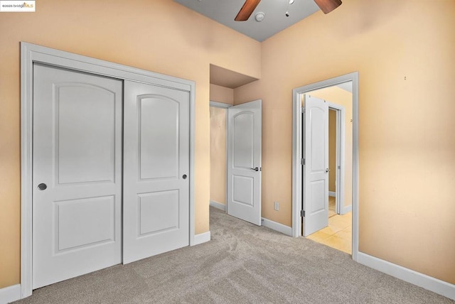 unfurnished bedroom with ceiling fan, light carpet, and a closet