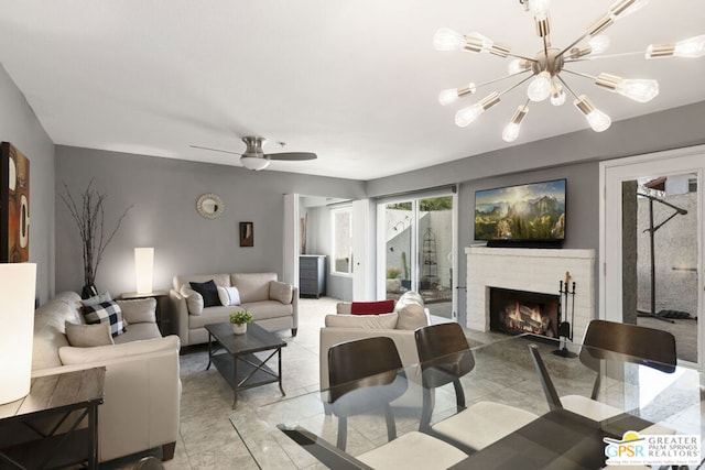 living room featuring ceiling fan with notable chandelier and a fireplace