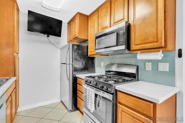 kitchen with dishwasher, light tile patterned floors, gas range oven, and decorative backsplash